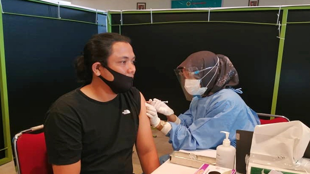 MAHASISWA asal Pekanbaru yang kuliah di Wuhan, China, Rio Alfi, saat disuntik vaksin di Pekanbaru, Senin (12/4/2021). 