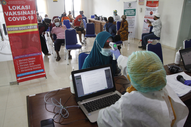 Petugas medis mengecek suhu tubuh penerima vaksin COVID-19 lansia di Rumah Sakit Gigi dan Mulut Soelastri, Solo, Jawa Tengah, Selasa (13/4/2021). Foto: Maulana Surya/Antara Foto