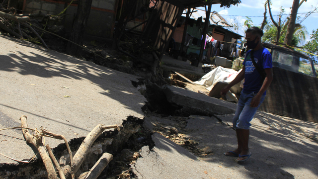 Seorang warga melintasi ruas jalan yang terbelah akibat longsor di Kupang, NTT, Rabu (14/4). Foto: Kornelis Kaha/ANTARA FOTO