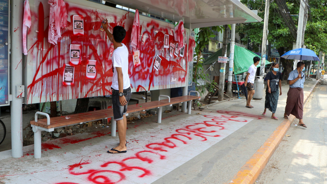 Seorang pengunjuk rasa anti-kudeta menggunakan cat merah saat dia menulis slogan di halte bus, di Yangon, Myanmar, Rabu (14/4). Foto: AP Photo