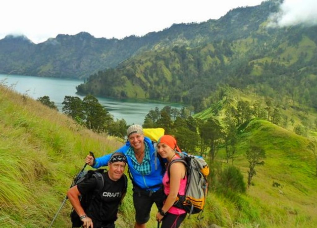 Tiga pendaki mancanegara saat mendaki Gunung Rinjani, dengan latar belakang Danau Segara Anak. Foto: Harley Sastha