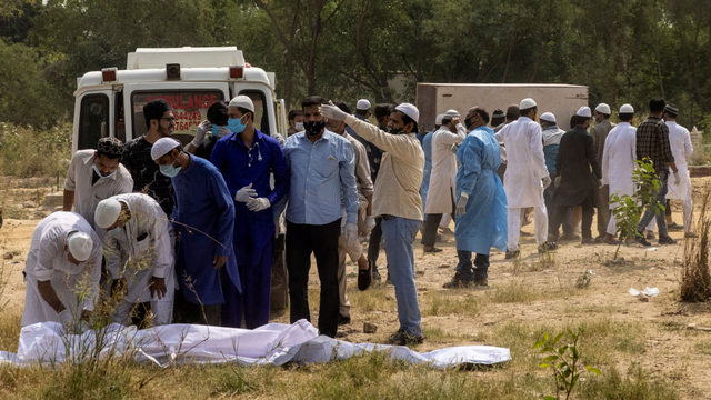 Sejumlah orang mengangkat jenazah COVID-19 sebelum dikubur di pemakaman di New Delhi, India, Jumat (16/4). Foto: Danish Siddiqui/REUTERS