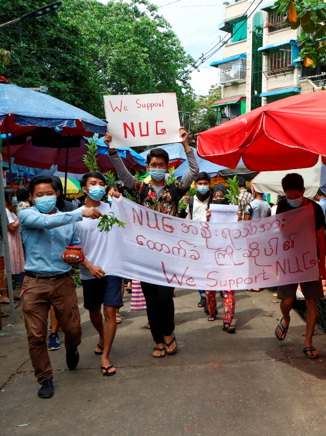 Pengunjuk rasa anti-kudeta memegang tanda bertuliskan "Kami Mendukung NUG" yang merupakan singkatan dari 'pemerintah persatuan nasional', di Yangon, Myanmar, Sabtu (17/ Foto: Stringer/REUTERS