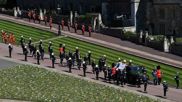 Anggota Keluarga Kerajaan berjalan di belakang mobil jenazah, sebuah Land Rover yang dimodifikasi khusus, di halaman Kastil Windsor selama pemakaman Pangeran Philip. Foto: Pool via REUTERS