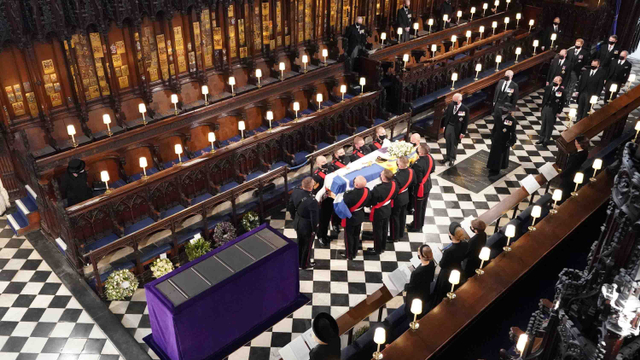 Ratu Elizabeth II menyaksikan para pengusung jenazah membawa peti mati Pangeran Philip di Kapel St George, Inggris. Foto: Pool via REUTERS