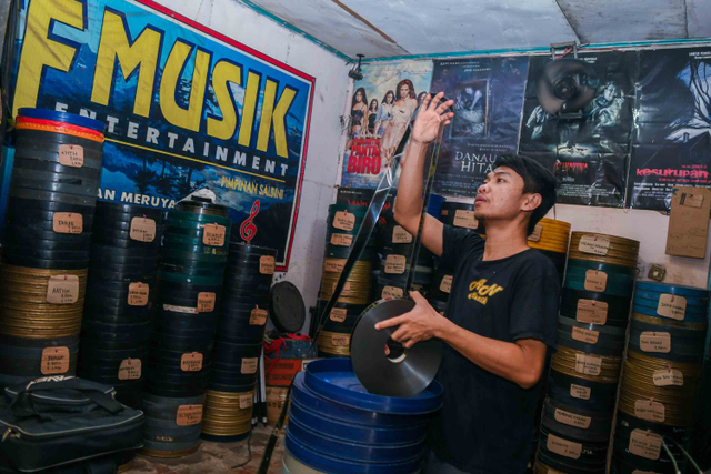 Abdul mengecek kondisi film 35mm untuk pemutaran film layar tancap. Foto: Galih Pradipta/ANTARA FOTO