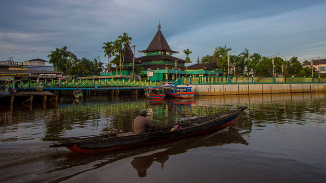 Sebuah perahu bermesin melintas di Sungai Kuin dengan latar belakang Masjid Sultan Suriansyah di Banjarmasin, Kalimantan Selatan, Minggu (18/4/2021). Foto: BAYU PRATAMA S/ANTARA FOTO