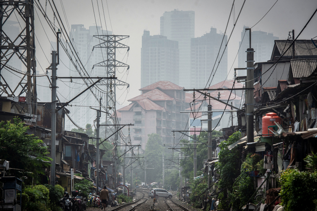 Deretan permukiman penduduk dengan latar belakang gedung bertingkat tersamar kabut polusi udara di Jakarta, Selasa (20/4/2021). Foto: Aprillio Akbar/ANTARA FOTO