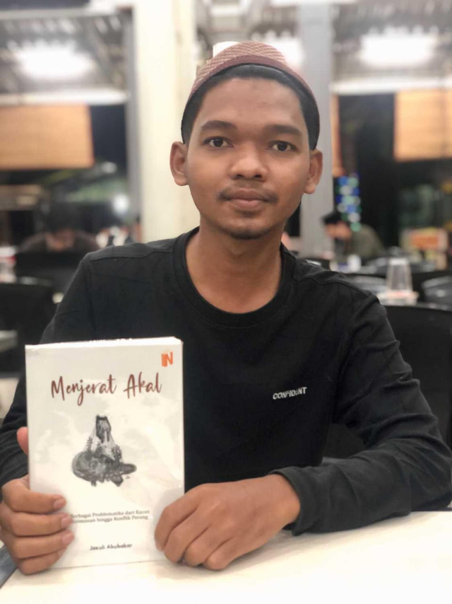 Guru dayah di Aceh, Jazuli Abubakar (24) berfoto dengan buku karyanya yang berjudul Menjerat Akal: Berbagai Problematika dari Kasus Keimanan hingga Konflik Perang. Foto: Dok. Pribadi
