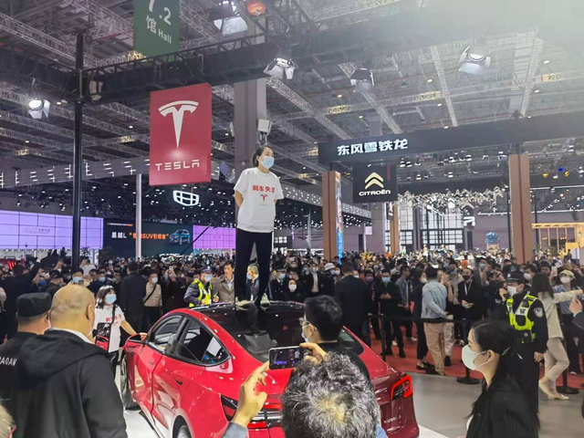 Seorang wanita protes dan menginjak mobil Tesla di pameran. Foto: dok. ShanghaiEye