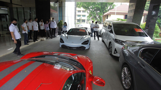 Petugas mengamati barang bukti mobil mewah Ferrari dan McLaren saat rilis kasus investasi ilegal E-Dinar Coin (EDC) Cash di Bareskrim Polri, Jakarta, Kamis (22/4/2021). Foto: Reno Esnir/ANTARA FOTO