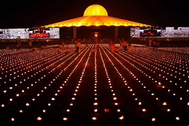 Biksu Buddha dari Kuil Dhammakaya menghadiri upacara meditasi pada Hari Bumi dan menyalakan 330.000 lilin dalam bentuk bumi di provinsi Pathum Thani, Thailand. Foto: Jorge Silva/REUTERS