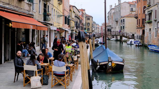 Sejumlah orang menikmati minuman malam aperitivo sambil duduk di bar luar ruangan, di Venesia, Italia, Senin (26/4). Foto: Manuel Silvestri/REUTERS