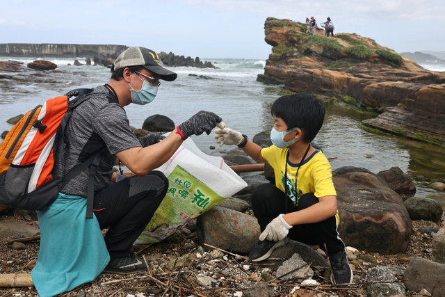 Seorang relawan bersama anaknya mengikuti acara bersih-bersih pantai di Keelung, Taiwan. Foto: Ann Wang/REUTERS