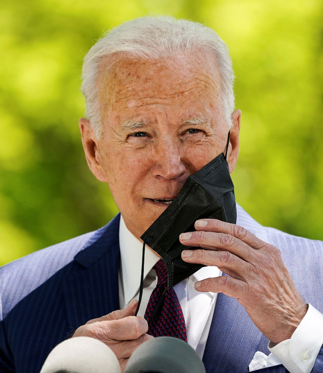 Presiden AS Joe Biden melepas masker saat melonggarkan penggunaan masker. Foto: Kevin Lamarque/Reuters