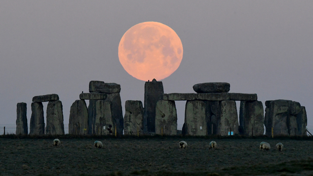 Bulan purnama, yang dikenal sebagai "Super Pink Moon", terletak di belakang lingkaran batu Stonehenge dekat Amesbury, Inggris, Selasa (27/4). Foto: Toby Melville/REUTERS