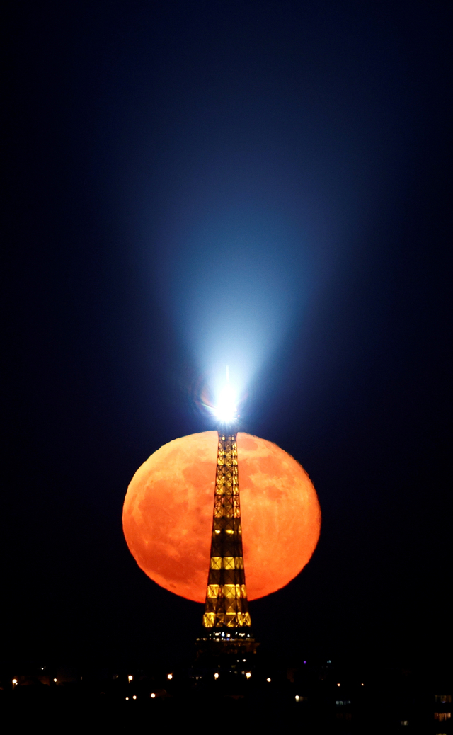 Bulan purnama atau pink super moon muncul di belakang Menara Eiffel di Paris, Prancis, Selasa (27/4). Foto: Christian Hartmann/REUTERS