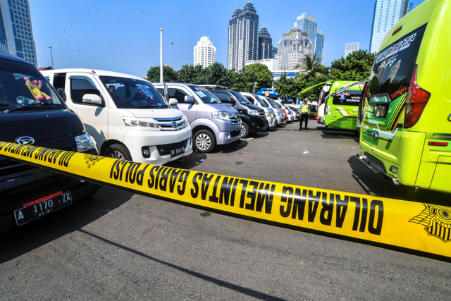 Petugas kepolisian memeriksa barang bukti kendaraan travel gelap di Lapangan Presisi Dit Lantas PMJ, Jakarta, Kamis (29/4). Foto: Muhammad Adimaja/ANTARA FOTO