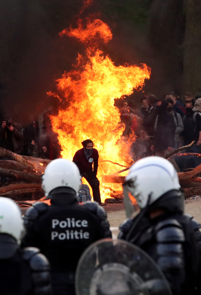 Api membara saat demonstran bentrokan dengan polisi saat pesta anti-penguncian di taman Bois de la Cambre/Ter Kamerenbos, di Brussel, Belgia, Sabtu (1/5). Foto: REUTERS/Yves Herman