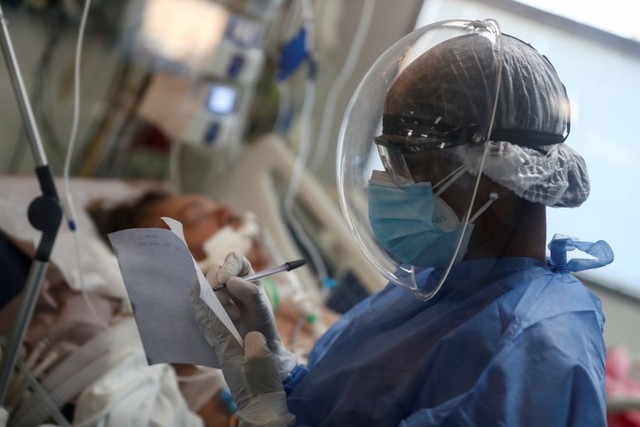 Petugas kesehatan memeriksa pasien terinfeksi virus corona di unit perawatan intensif Rumah Sakit di Buenos Aires, Argentina. Foto: Agustin Marcarian/REUTERS