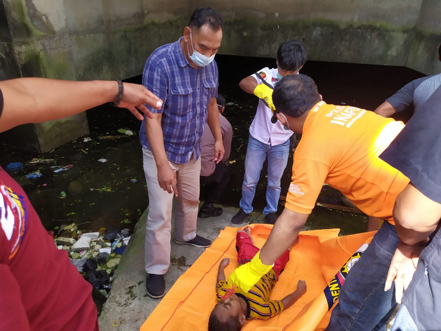Petugas mengevakuasi bocah yang tewas tenggelam di basement Komplek Pertokoan Nirmala Square. (foto istimewa)