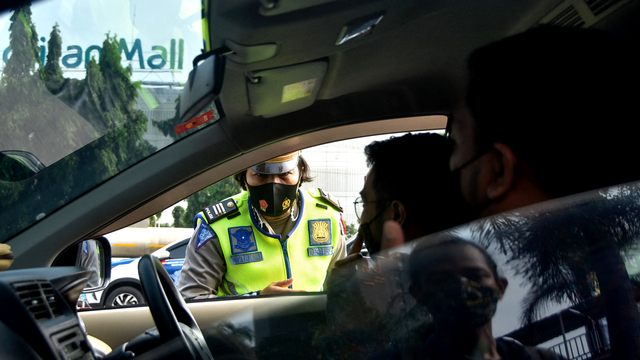 Petugas polisi memeriksa kendaraan yang akan menuju keluar ibu kota, di pos pemeriksaan di Bekasi, Jawa Barat, Kamis (6/5). Foto: Rezas/AFP