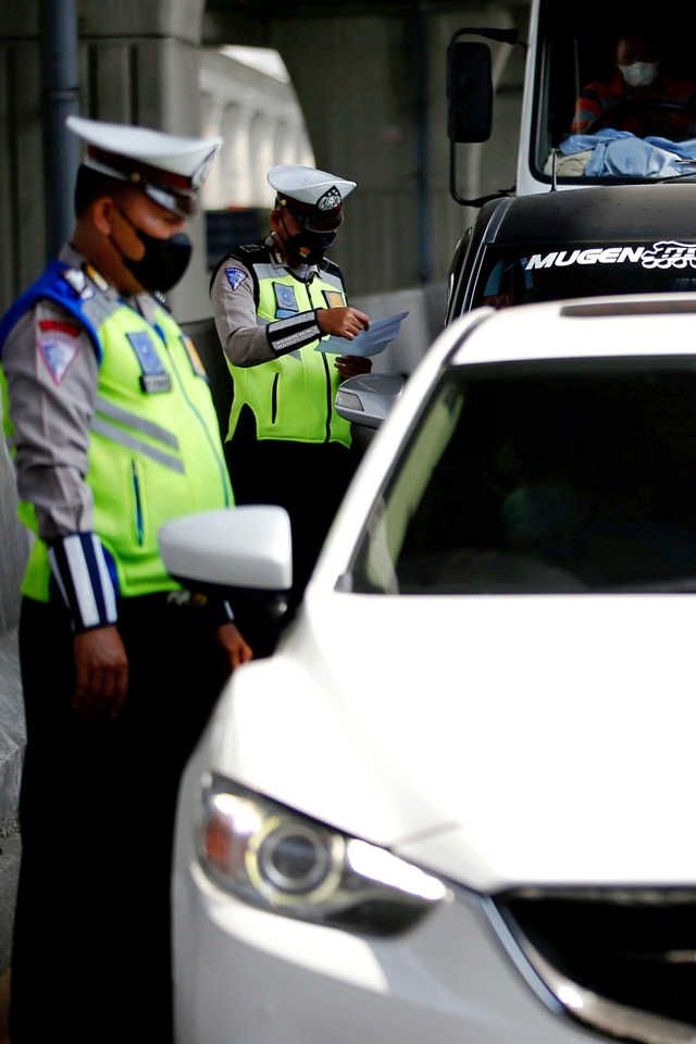 Petugas polisi memeriksa mobil di pos pemeriksaan kendaraan, di Karawang, Jawa Barat, Kamis (6/5). Foto: Willy Kurniawan/REUTERS