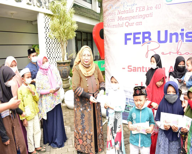 Dekan FEB Unisma, Nur Diana SE MSi (tengah), menyerahkan santunan kepada anak yatim piatu. Foto: dok