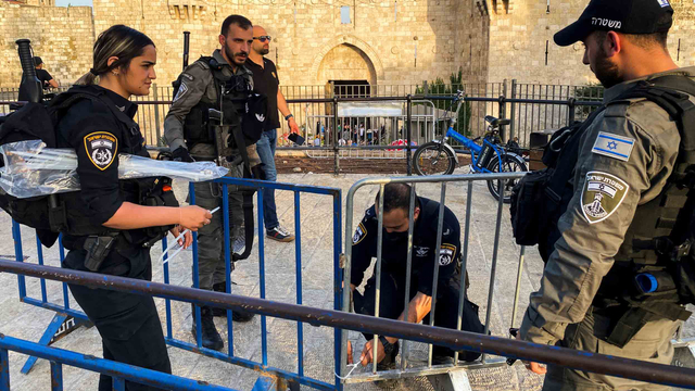 Petugas polisi Israel mengikat barikade bersama di Gerbang Damaskus dalam persiapan untuk Lailatul qadar di Kota Tua Yerusalem (8/5). Foto: Stephen Farrell/Reuters