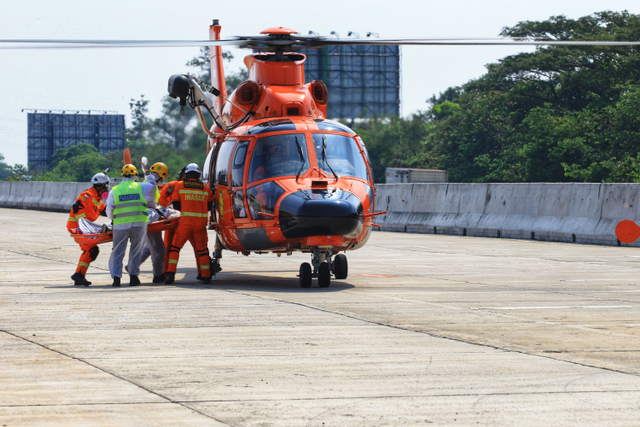 Petugas mengevakuasi korban ke dalam helikopter saat simulasi penyelamatan kecelakaan di jalan tol dengan menggunakan rescue udara di Jalan Tol Jagorawi KM 19B, Senin (10/5). Foto: Aditia Noviansyah/kumparan