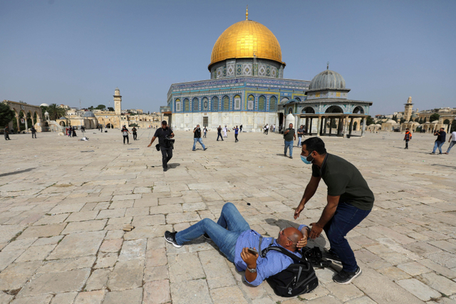 Sejumlah warga berlari selama bentrokan dengan warga Palestina di kompleks Masjid Al-Aqsa di Yerusalem.  Foto: Ammar Awad/REUTERS