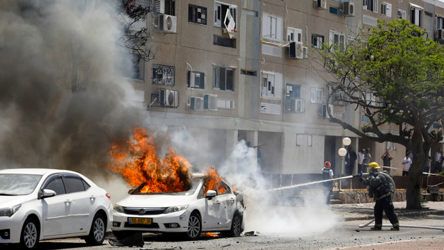 Petugas pemadam kebakaran Israel memadamkan mobil yang terbakar setelah roket diluncurkan dari Jalur Gaza, di Ashkelon, Israel selatan, Selasa (11/5). Foto: Nir Elias/REUTERS