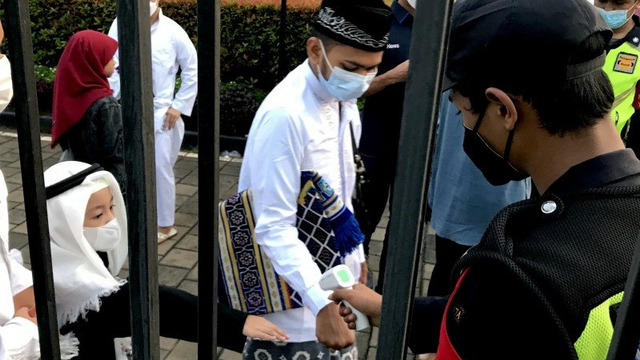 Petugas keamanan memeriksa suhu tubuh jamaah yang akan mengikuti salat Idul Fitri di Masjid Al-Azhar, Jakarta, Kamis (13/5/2021). Foto: Genta Tenri Mawangi/ANTARA