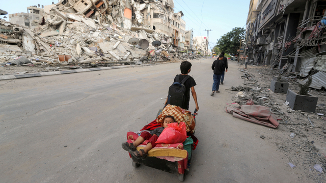 Seorang anak laki-laki Palestina menarik gerobak yang membawa saudara laki-lakinya saat mereka melarikan diri, di Jalur Gaza utara, Jumat (14/5). Foto: Mohammed Salem/REUTERS