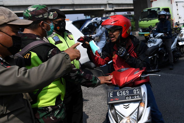 Petugas gabungan menegur pengendara motor yang tidak memakai masker di pos penyekatan mudik Sumber Artha, Bekasi, Jawa Barat, Jumat (14/5). Foto: Sigid Kurniawan/ANTARA FOTO
