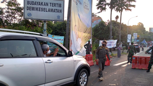 Petugas melakukan pemeriksaan kendaraan di pos penyekatan mudik di jalan menuju Puncak Bogor, Sabtu (15/5). Foto: kumparan