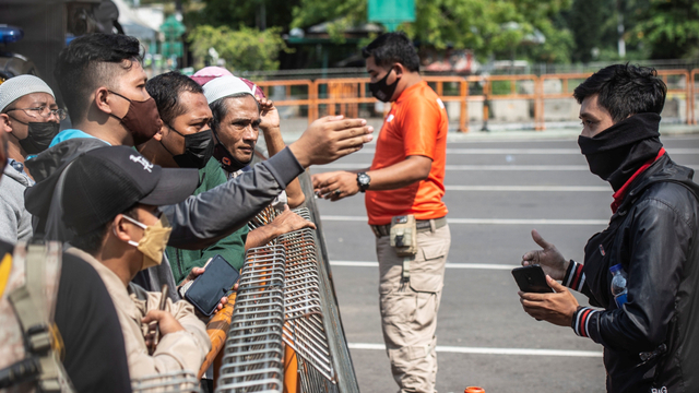 Petugas memberikan imbauan kepada warga yang akan berwisata untuk kembali pulang di depan pintu masuk Ancol Taman Impian, Jakarta, Sabtu (15/5/2021). Foto: Aprillio Akbar/ANTARA FOTO