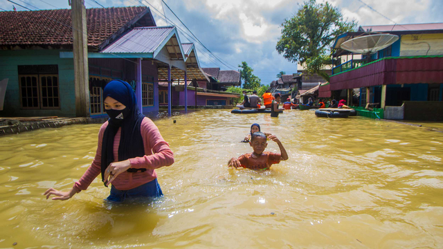 Sejumlah warga menerobos banjir yang merendam permukiman di Jalan Biduri, Kecamatan Satui, Kabupaten Tanah Bumbu , Kalimantan Selatan, Sabtu (15/5/2021). Foto: BAYU PRATAMA S/ANTARA FOTO