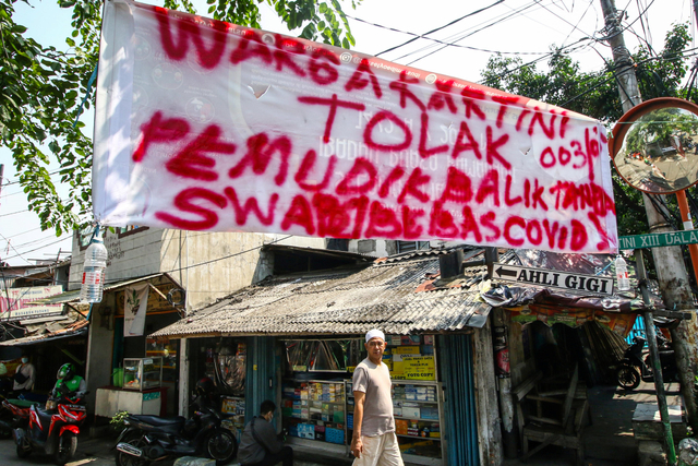 Warga melintas di dekat spanduk peringatan untuk pemudik di kawasan Sawah Besar, Jakarta, Minggu (16/5/2021). Foto: Rivan Awal Lingga/Antara Foto