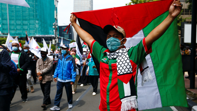 Anggota organisasi buruh mengibarkan bendera Palestina saat protes terhadap Israel di luar gedung PBB di Jakarta, Selasa (18/5). Foto: Ajeng Dinar Ulfiana/REUTERS