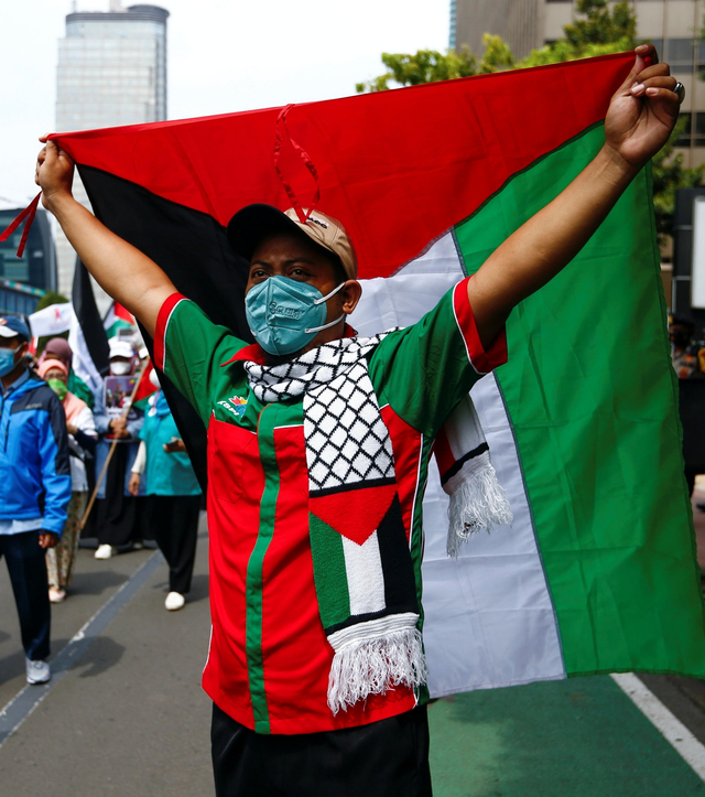 Anggota organisasi buruh mengibarkan bendera Palestina saat demo solidaritas Palestina di luar gedung PBB di Jakarta, Selasa (18/5). Foto: Ajeng Dinar Ulfiana/REUTERS
