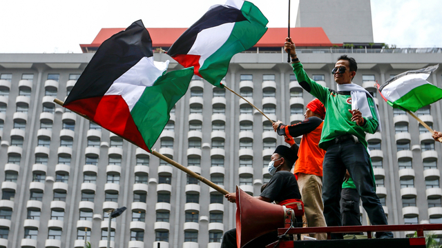 Sejumlah anggota organisasi buruh mengibarkan bendera Palestina saat protes terhadap Israel di luar gedung PBB di Jakarta, Selasa (18/5). Foto: Ajeng Dinar Ulfiana/REUTERS