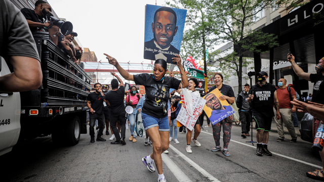 Seorang wanita mengangkat poster saat mengikuti peringatan satu tahun kematian George Floyd, di Minneapolis, Minnesota, AS, Minggu (23/5). Foto: Nicholas Pfosi/REUTERS 