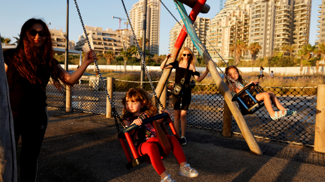 Para wanita bermain dengan anak-anak di ayunan di taman bermain saat gencatan senjata Israel-Hamas berlaku, di Ashkelon, Israel, Minggu (23/5). Foto: Amir Cohen/REUTERS