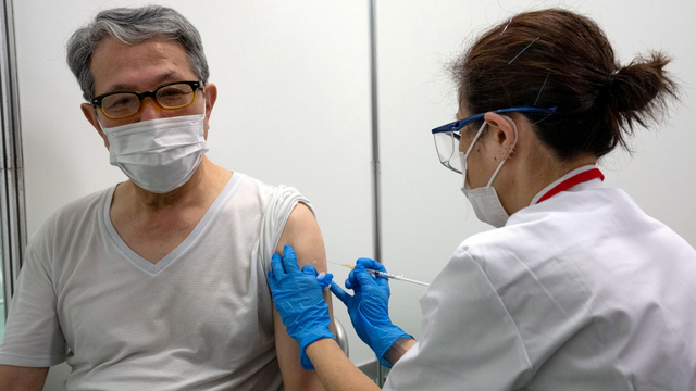 Seorang lansia menerima vaksin corona Moderna di pusat vaksinasi massal yang baru dibuka di Tokyo, Jepang, Senin (24/5). Foto: Carl Court/Pool via REUTERS