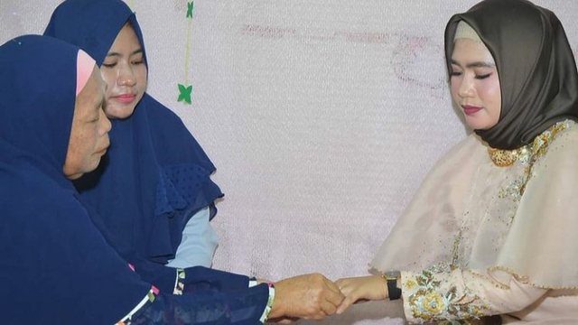 Proses pemasangan cincin oleh calon ibu mertua kepada pihak perempuan sebagai tanda telah terjadinya proses lamaran. (Sumber: Dokumen Pribadi)