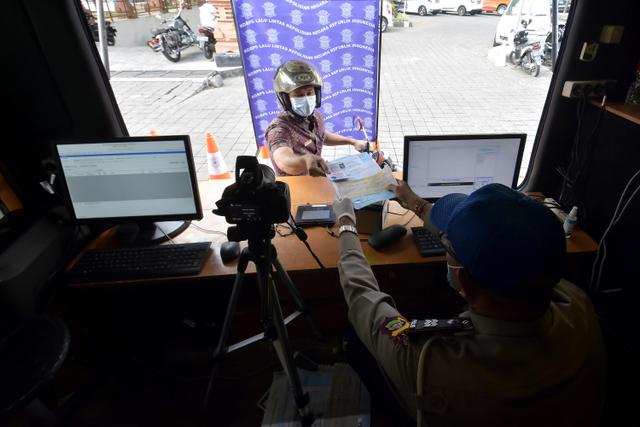 Petugas Satlantas Polresta Denpasar melayani warga yang mengurus perpanjangan Surat Izin Mengemudi (SIM) dengan sistem "drive thru" di Denpasar, Bali. Foto: Nyoman Hendra Wibowo/ANTARA FOTO