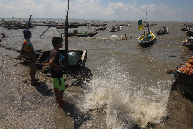 Nelayan mengamati perahu saat terjadi gelombang tinggi dan angin kencang di pesisir Bulak, Surabaya, Jawa Timur, Kamis (27/5).  Foto: Didik Suhartono/ANTARA FOTO