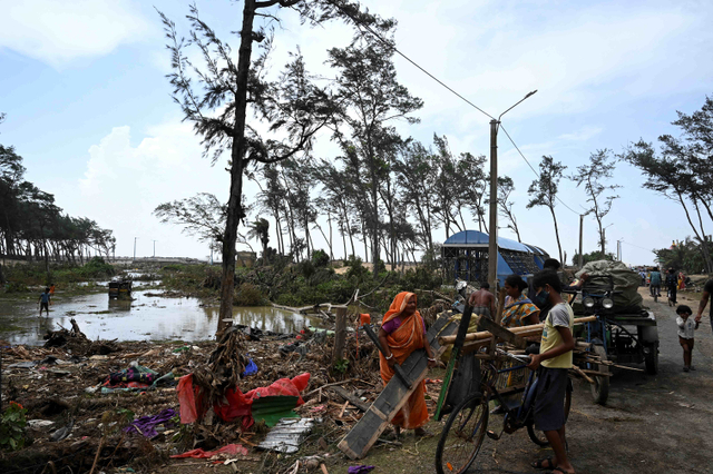 Penduduk mengumpulkan puing-puing dari daerah yang rusak di dekat pantai setelah Topan Yaas menghantam pantai timur India di Teluk Benggala di Digha. Foto: Dibyangshu Sarkar/AFP