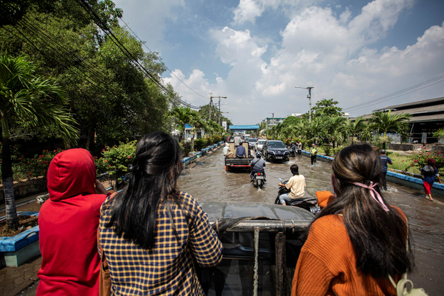 Warga menumpang mobil bak saat melintasi banjir rob di kawasan Pelabuhan Perikanan Muara Baru, Jakarta, Jumat (28/5/2021). Foto: Dhemas Reviyanto/Antara Foto